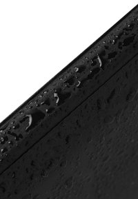Fekete felület vízcseppekkel, sima textúrával, elegáns dizájnnal és látható lefolyónyílásokkal a széleken.