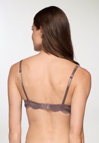 Bra con schienale in pizzo di colore marrone tenue, dotato di spalline in satin regolabili, con bordi in pizzo floreale e chiusura con gancio e occhiello.