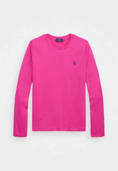 Ilgų rankovių marškinėliai iš ryškiai rožinės medvilnės, su apvalia iškirpte ir mažuoju tamsiai mėlynu siuvinėtų logotipu kairėje krūtinės pusėje.