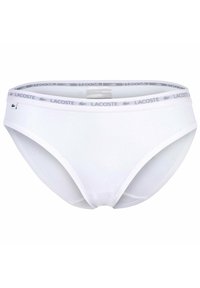 Slip di cotone bianco con un morbido elastico in vita, caratterizzato da un logo "LACOSTE" in grigio ripetuto e un piccolo emblema di coccodrillo verde sul lato.