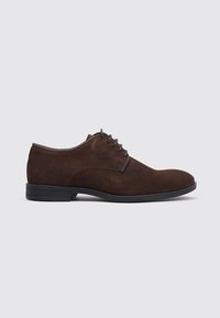Zapato de vestir para hombre en ante marrón con cordones, tacón bajo y suela negra, mostrado en perfil lateral sobre un fondo gris claro.