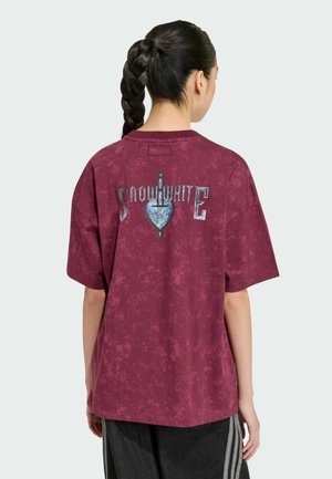 Kobieta z zaplecionymi włosami widziana od tyłu, ubrana w bordowy t-shirt tie-dye z "Snow White" oraz grafiką serca i sztyletu na plecach.