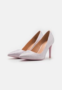 Talons hauts argentés scintillants avec un design à bout pointu, présentant une doublure intérieure rose lisse et un talon aiguille rose brillant.