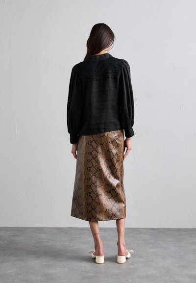 Zwart langemouwen top met een getextureerde kantkraag; bruin slangenpatroon midi rok; gladde lederen textuur; eenvoudige blokhak schoenen.