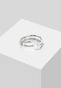 Hõbedane metallist sõrmus, millel on keerutatud avatud disain kahe siledalt kaarduvast ribast, mis moodustavad elegantse ja minimalistliku kuju.