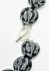 Collana nera con perle di vetro texture, caratterizzata da motivi argentati e chiusa con un gancio a toggles in argento.