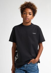 Sort bomulds T-shirt med korte ærmer og rund halsudskæring, med hvid logo tekst på brystet og et iøjnefaldende grafisk print på siden.