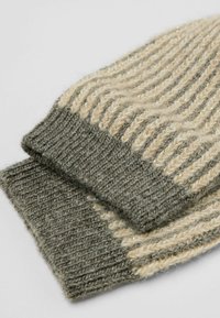 Knitted gloves in light beige and dark green, featuring ribbed texture and subtle shimmer. The cuff is thick and cozy for warmth.