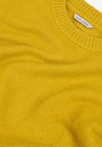 Gelber Wollpullover mit einem gerippten Rundhalsausschnitt, glatter Textur und subtiler Farbvariationen im Stoff. Etikett sichtbar: Dan John.