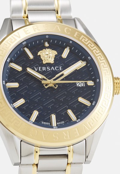 Gold and silver stainless steel watch featuring a dark blue textured dial, gold hour markers, and a Medusa emblem at the center.