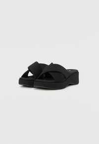 Mustad mustanditega mustad sussid, millel on paks platvorm, laiad ristiäärised pehmest materjalist ja tekstureeritud jalatugi mugavuse tagamiseks.