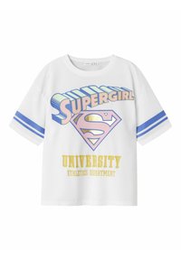 T-shirt oversize blanc avec le texte "Supergirl" et un logo en forme de diamant. Des accents bleus et jaunes mettent en valeur le texte "DÉPARTEMENT DES SPORTS UNIVERSITAIRES".
