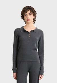 Maglione grigio a coste con colletto, tre bottoni marroni e maniche lunghe, caratterizzato da una silhouette aderente e una texture morbida.