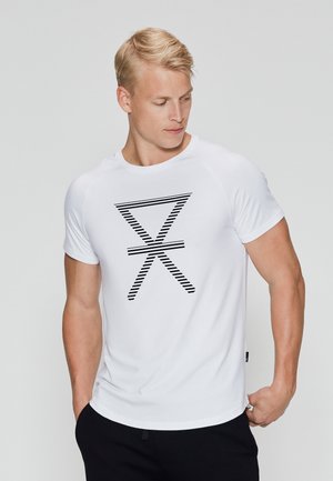 Hvid t-shirt med kort ærme, der har et sort stribet grafisk design foran. Glat stof og tætsiddende form, kombineret med mørke bukser.