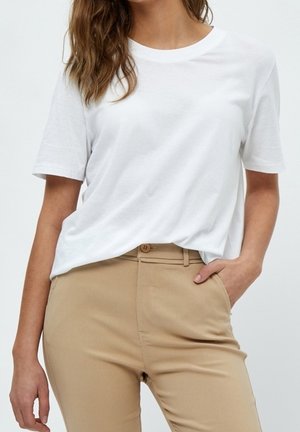 Witte katoenen T-shirt met een ronde halslijn en korte mouwen, gecombineerd met beige broek met een knoop aan de voorkant en zakken.