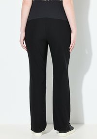 Zwarte broek met een relaxte pasvorm en wijde benen, met een hoge tailleband. Zacht, rekbaar materiaal en minimale naden zorgen voor een soepele silhouette.
