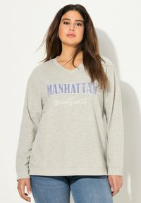 Felpa grigia a maniche lunghe con scollatura a V, con la scritta "MANHATTAN" in lettere viola e "sweetheart" in corsivo bianco. Tessuto morbido.