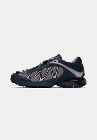 Zapatillas de running para hombre con una parte superior de malla en azul oscuro y gris, acentos reflectantes y una suela de goma negra. Cuenta con un sistema de cordones rápido para el cierre.