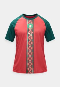 Κόκκινο και πράσινο αθλητικό πουκάμισο με κοντά μανίκια, διακοσμητική κάθετη ρίγα, λογότυπο Puma και έμβλημα ποδοσφαίρου κοντά στον γιακά.