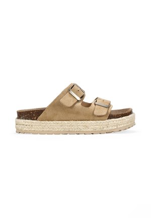 Sandalia tipo slide de doble tira en ante beige con hebillas plateadas, suela de plataforma espadril de yute gruesa y plantilla de corcho.