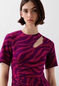 Fuchsia en paarse jurk met korte mouwen met een tijgerstrepenpatroon, voorzien van een zijsnede en geplooide details bij de taille.