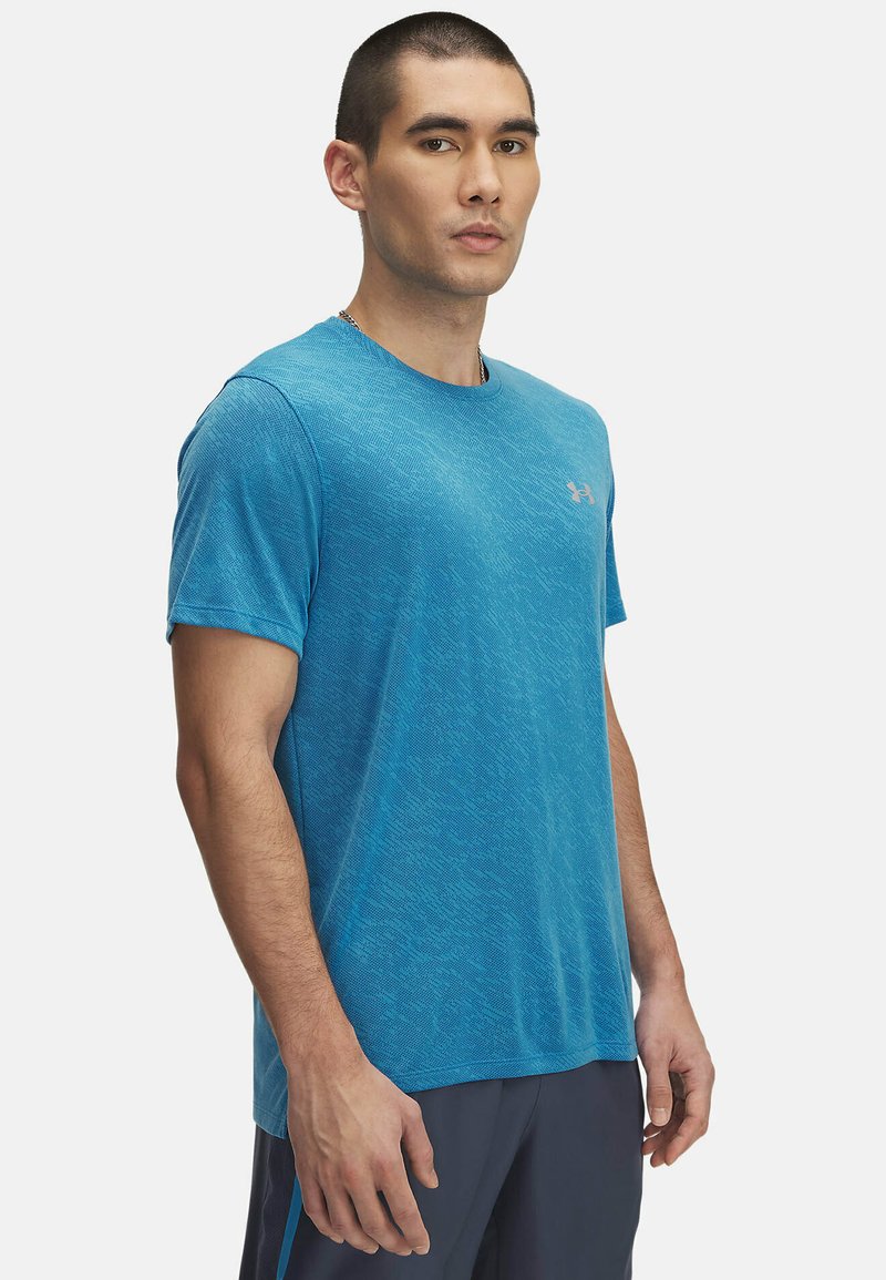 Camiseta deportiva azul con un patrón texturizado, de mangas cortas y cuello redondo. Presenta un pequeño logo en el pecho izquierdo.