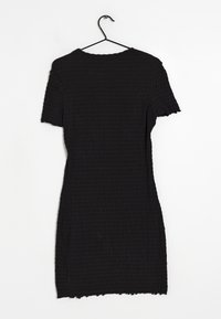 Svart kortärmad klänning på en galge, med textilerat material som har ett krusigt mönster och råa kanter vid halsringningen och fållen.