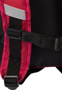 Sezione dello zaino nero e rosso con una cinghia a rete, clip in plastica, striscia riflettente e tessuto testurizzato. Caratterizzato da cuciture robuste e materiale durevole.