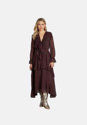 Largo vestido burdeos oscuro con volantes en capas, escote profundo en V y cintura ceñida con cinturón. Mangas largas transparentes y falda fluida, combinado con botas plateadas hasta la rodilla.