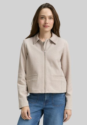 Veste beige courte avec col, fermeture éclair à l'avant et deux poches latérales. Fabriquée dans un tissu doux avec une texture lisse.