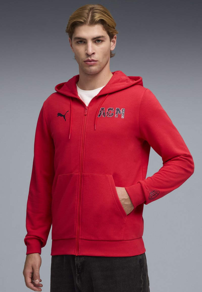 Κόκκινο hoodie με φερμουάρ, κατασκευασμένο από μείγμα βαμβακιού. Διαθέτει τσέπες τύπου καγκουρό, κεντημένο λογότυπο "AGM" και λογότυπο Puma στο στήθος. Απλός σχεδιασμός με ριμπ μανσέτες.