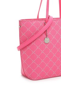 Sac fourre-tout rose avec un motif en losanges et de petits cercles, doté d'une longue bandoulière et d'un charm argenté rond suspendu à l'avant.