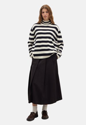 Pull rayé blanc et marine, col roulé côtelé, avec une coupe décontractée. Associé à une jupe noire longueur genoux et des chaussures marron.