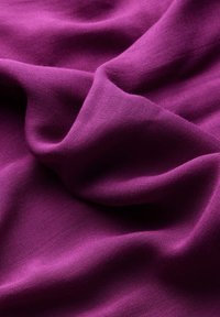 Violetti kangas, jossa on sileä pinta, vähäisellä kiillolla ja riippuvilla laskoksilla. Materiaali näyttää pehmeältä ja kevyeltä, sopii vaatteisiin.