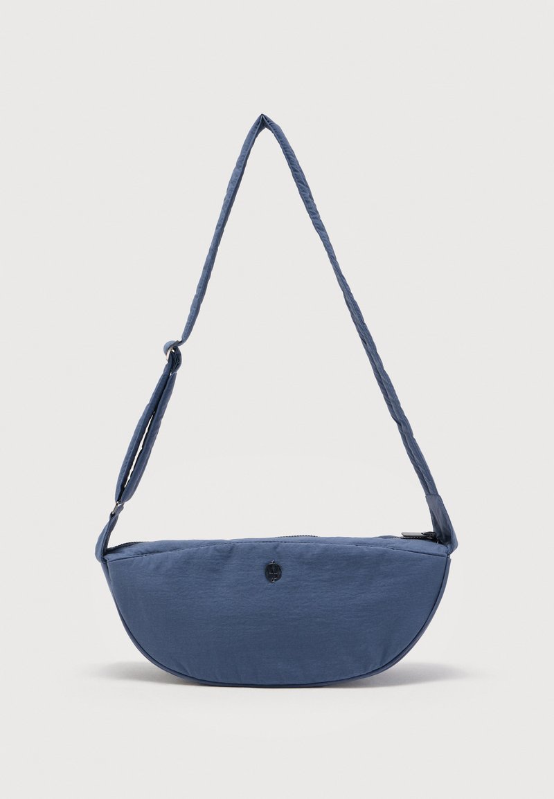 Μπλε τσαντάκι χιαστί σε σχήμα μισοφέγγαρου με ρυθμιζόμενο λουρί και φερμουάρ στην κορυφή, απεικονίζεται μπροστά σε απλό ανοιχτό φόντο.