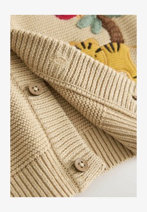 Cardigan bej tricotat cu tiv stratificat, prevăzut cu nasturi din lemn și un model texturat. Designul floral brodat accentuează țesătura.