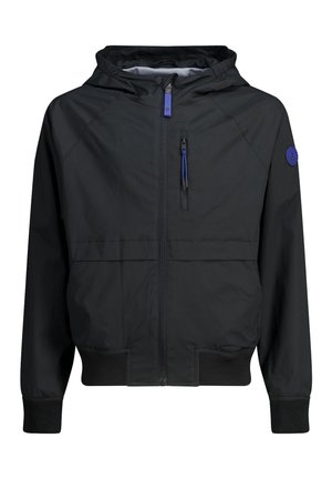 Czarna kurtka z kapturem, zapinana na przedni zamek, z kieszenią na piersi zamykaną na zamek, ściągaczami przy mankietach i dole, oraz okrągłą niebieską naszywką z logo na lewym rękawie.