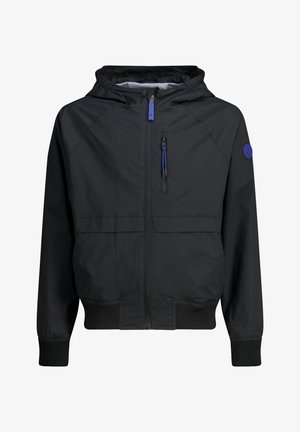 Czarna kurtka z kapturem, zapinana na przedni zamek, z kieszenią na piersi zamykaną na zamek, ściągaczami przy mankietach i dole, oraz okrągłą niebieską naszywką z logo na lewym rękawie.