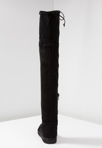 Botte noire au-dessus du genou en daim doux, avec un design vertical lisse, un cordon ajustable en haut et une fermeture éclair sur le côté.