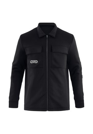 Chaqueta negra con cremallera, dos bolsillos con solapa en el pecho y un logo blanco "JAKO" en el área del bolsillo izquierdo.