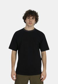T-shirt nero a maniche corte realizzato in cotone. Presenta un colletto a costine e un dettaglio logo discreto sul davanti. Vestibilità comoda e texture morbida.