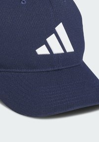 Marineblauwe pet van een gestructureerde stof, met een verhoogd wit Adidas-logo. Gebogen klep en doorgestikte accenten versterken het ontwerp.