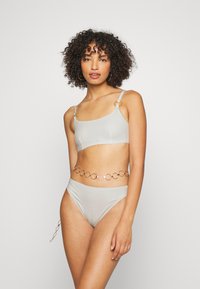 Conjunto de bikini cinza claro com um acabamento texturizado, apresentando detalhes em ouro nas alças e um cinto em corrente correspondente com elos circulares.