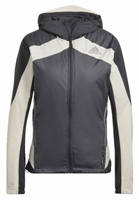 Chaqueta con capucha Adidas en gris oscuro y blanco roto, con cremallera completa al frente y bolsillos laterales, que cuenta con la tecnología de tejido Wind.RDY.