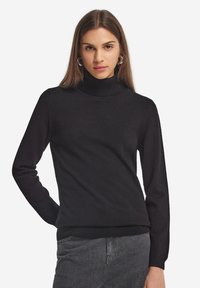 Schwarzer Rollkragenpullover aus weichem Material, enganliegend, mit langen Ärmeln und geripptem Saum, vor einem weißen Hintergrund präsentiert.