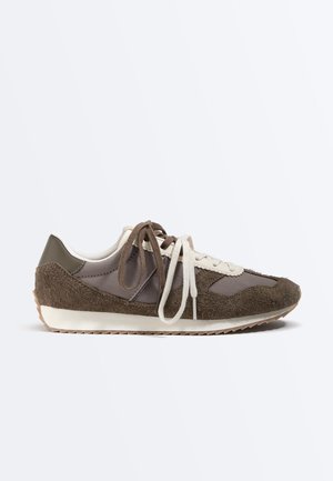 Baskets en daim et tissu marron et gris avec lacets blancs et marron, semelle blanche et semelle extérieure en caoutchouc texturé.