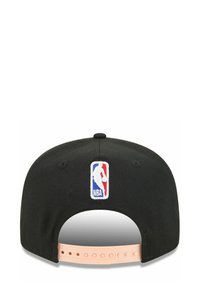 Casquette de baseball noire avec un logo NBA brodé à l'arrière et une fermeture ajustable à pression de couleur rose clair. Texture de tissu lisse.