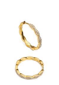 Pendientes de aro en tono dorado con un diseño ondulado, adornados con circonitas transparentes a lo largo de un borde. Acabado liso con textura pulida.