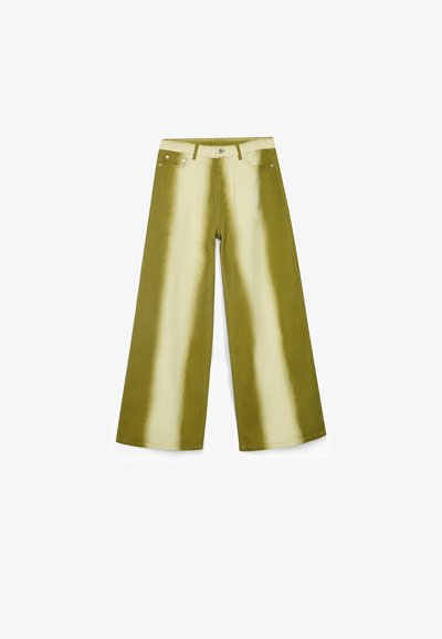 Pantalones de pierna ancha con un acabado brillante en verde oliva que presentan una franja vertical más clara en contraste, bolsillos clásicos y detalles en metal plateado.