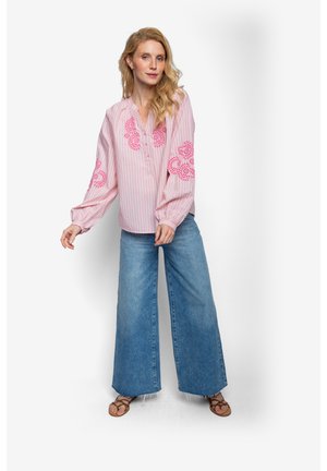 Różowa bluzka w paski z kwiatową haftem na rękawach, dobrana do szerokich dżinsów o kroju szerokie nogawki. Lekki materiał, luźny krój i casualowe obuwie.